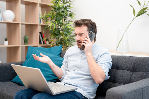 Angry man having problems on line talking on the phone with support service