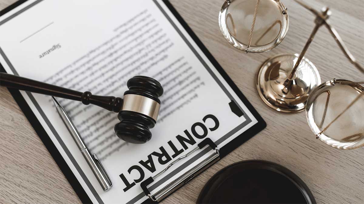 A close-up view of a legal contract on a clipboard with a gavel on top and a pen beside it