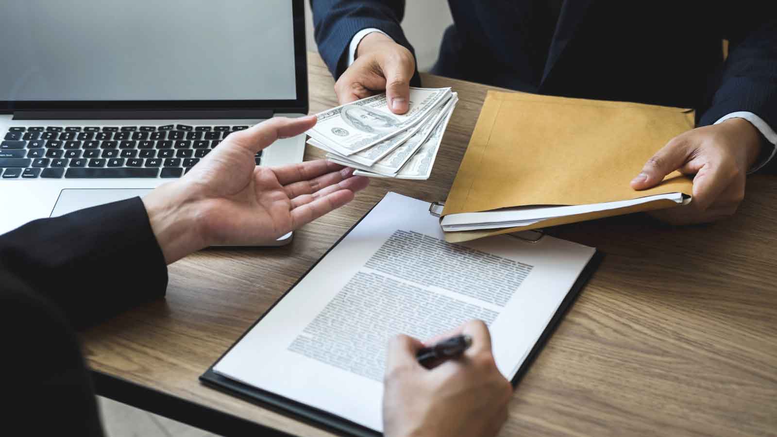  Two people exchanging money and documents over a contract on a desk