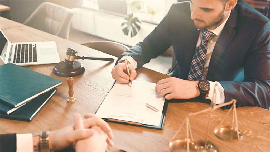 Attorney signing legal documents at a wooden desk.