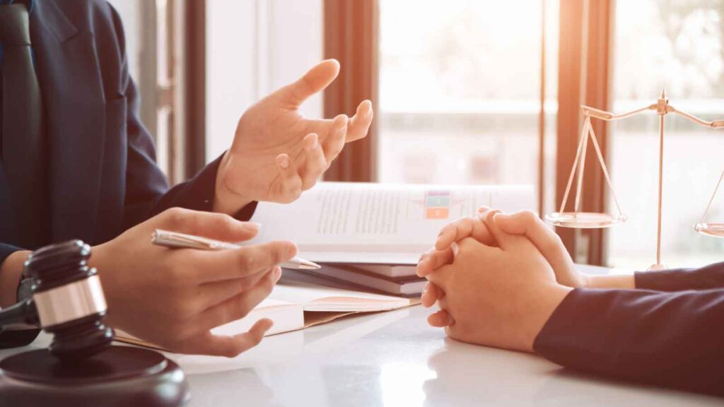 A lawyer discusses legal matters with a client at a desk.