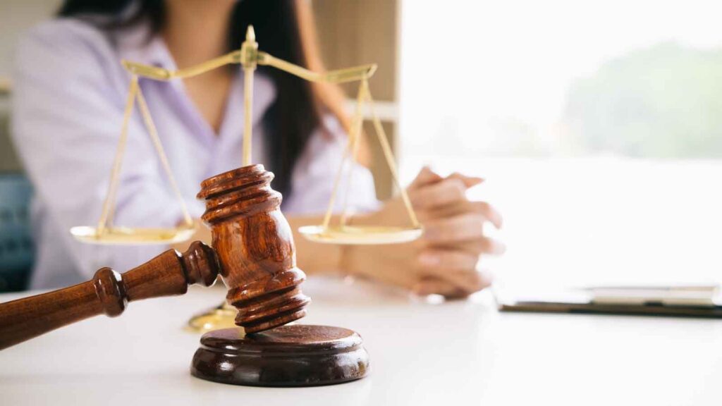  Gavel and justice scale in front of a seated woman.