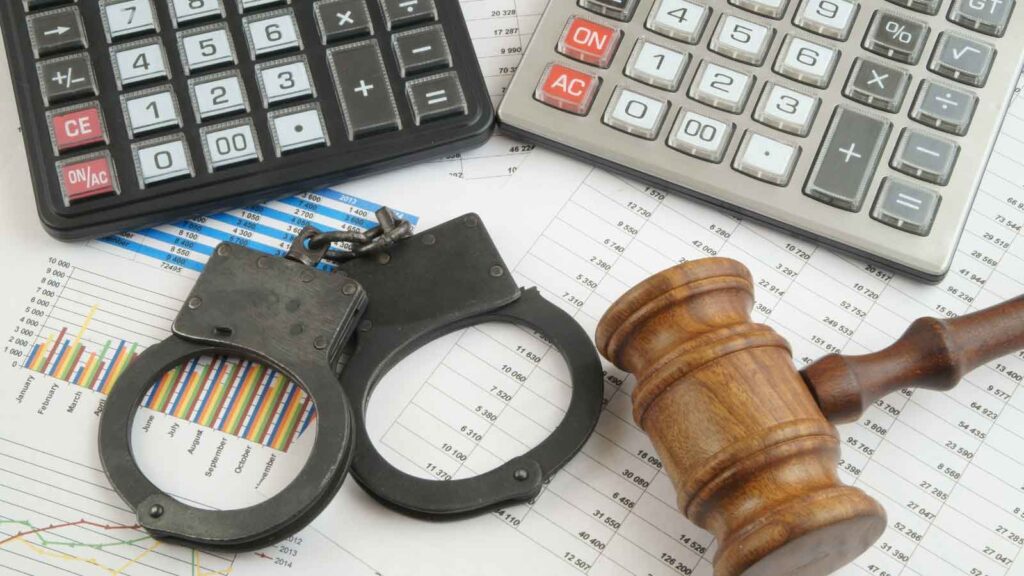 Handcuffs, gavel, and calculators on financial documents.