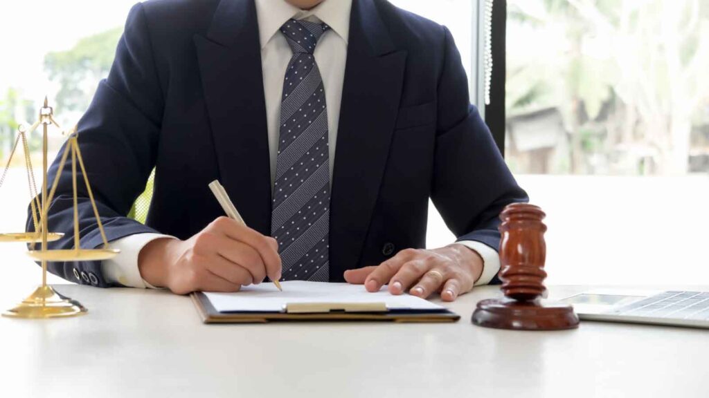 Lawyer in suit writing on legal documents at a desk.