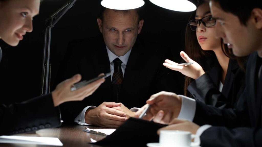 Business team in serious discussion under desk lamps.