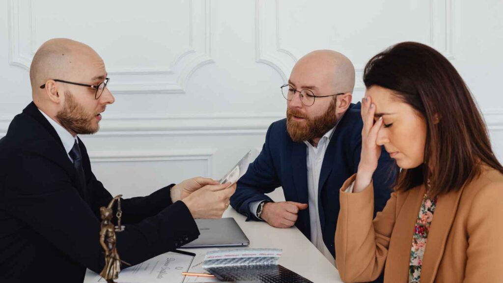 Lawyer discusses documents with concerned clients at a desk.