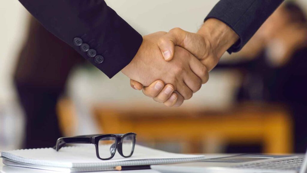 Two professionals shaking hands over a business deal.