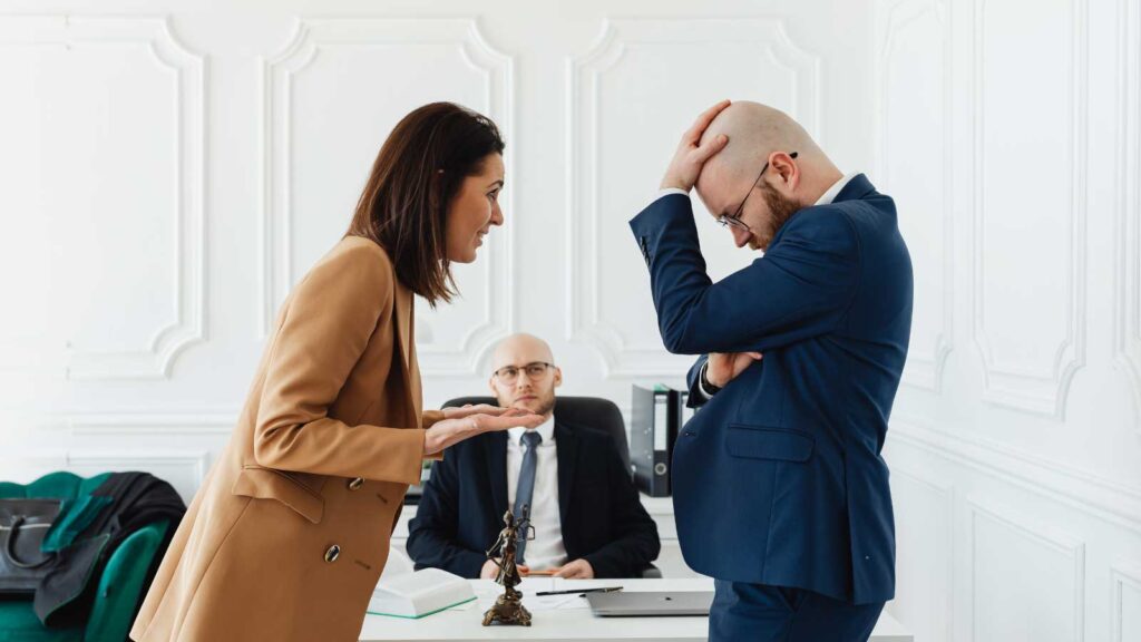 Woman speaking to distressed man during a serious office meeting.