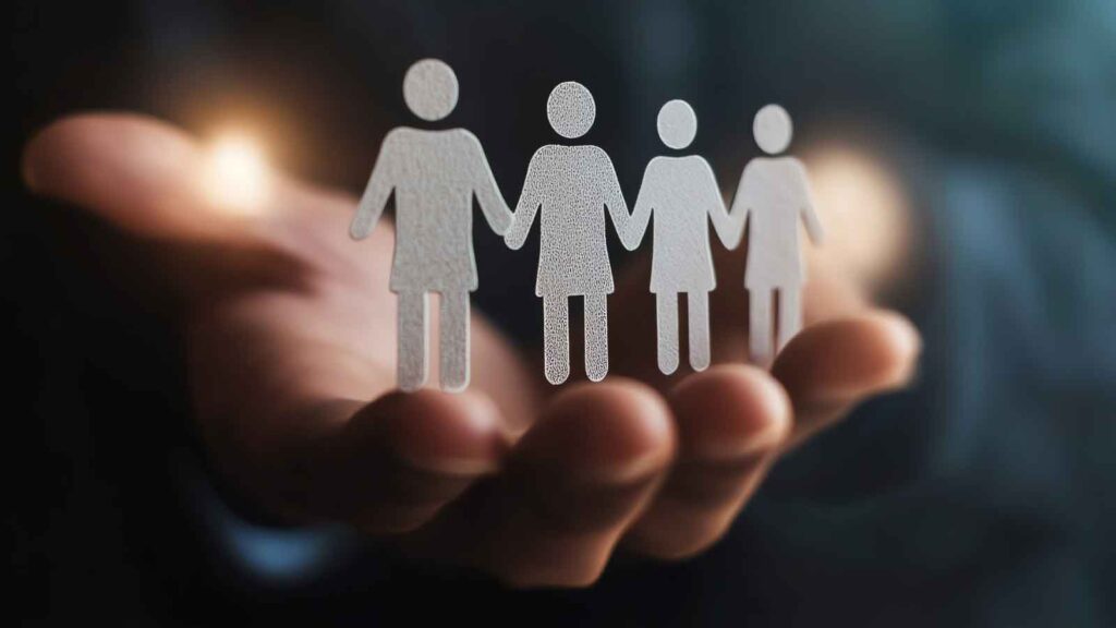 A hand holding paper cutout figures representing a group of people.