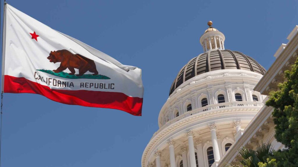 California state flag waves near Capitol building.