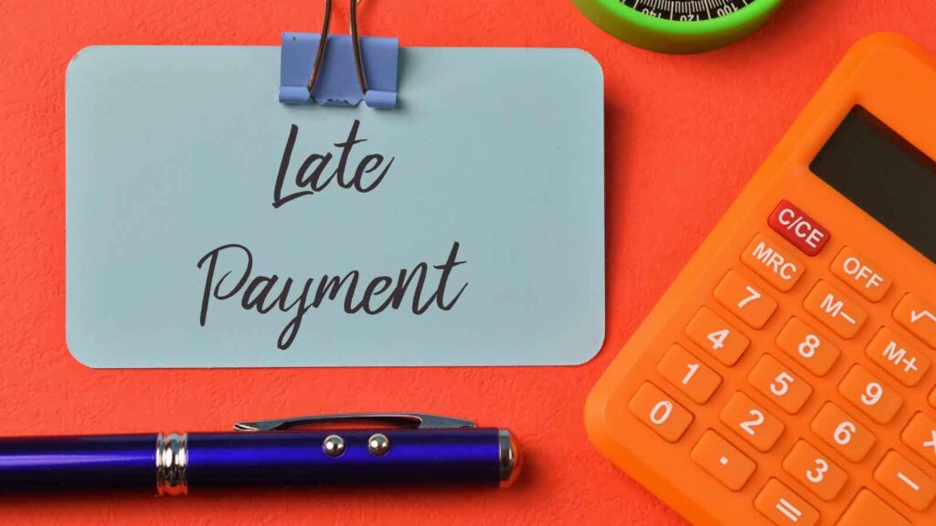 Card with _Late Payment_ text beside calculator and pen.