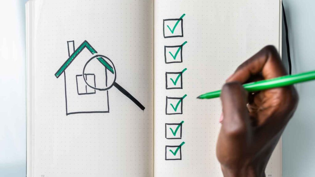Hand checking off boxes on a real estate inspection checklist.